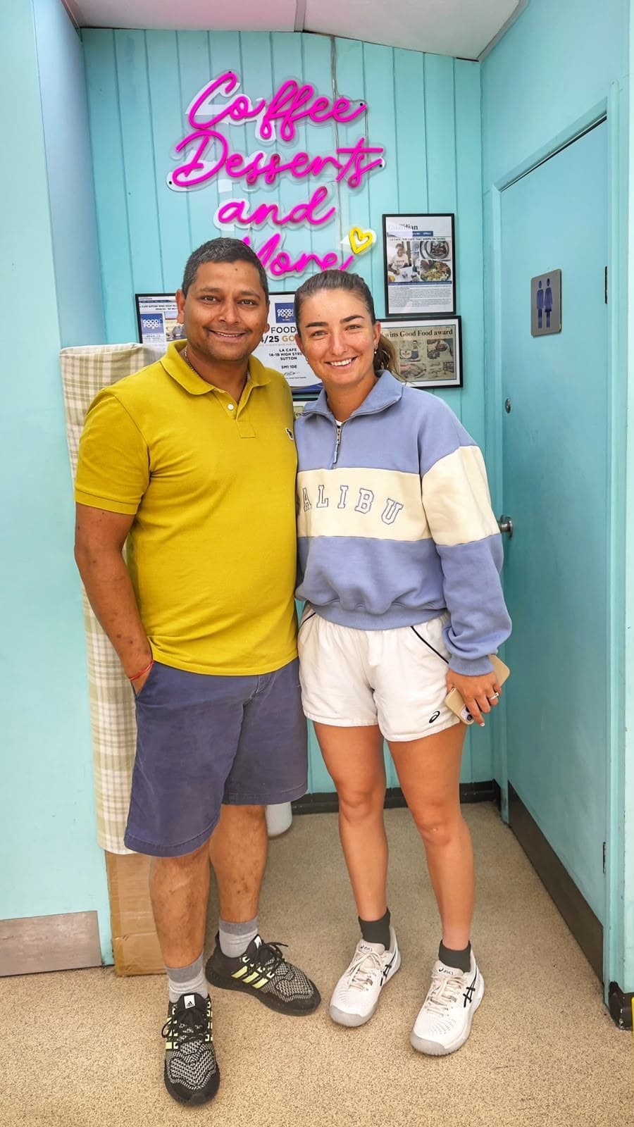 Wimbledon player Jessica Failla with owner Ankur Baria in front of the neon sign at LA Cafe